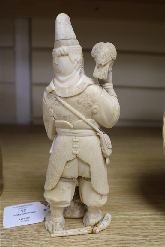 A Japanese carved ivory okimono of a huntsman, Meiji period, holding a hawk and a brace of birds